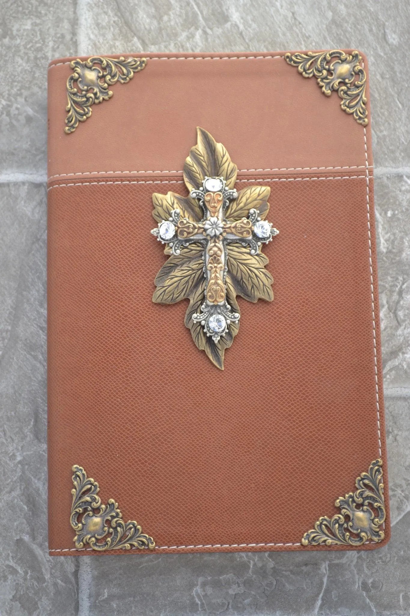Brown Bible with jeweled gold cross, ornate metal corners, and leaf accents on cover
