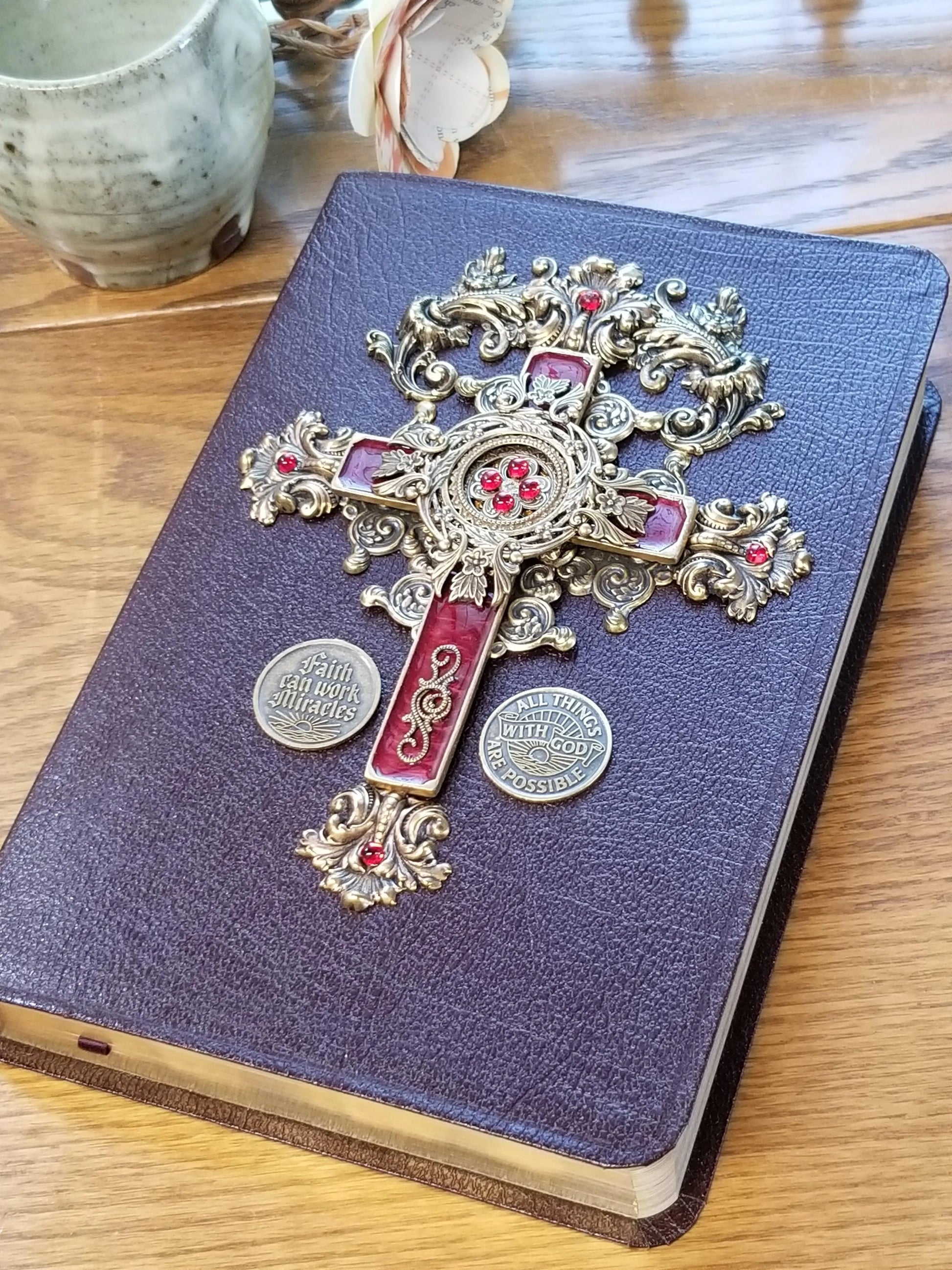 Jeweled Bible with ornate gold cross and red gems on brown cover, inspirational coins