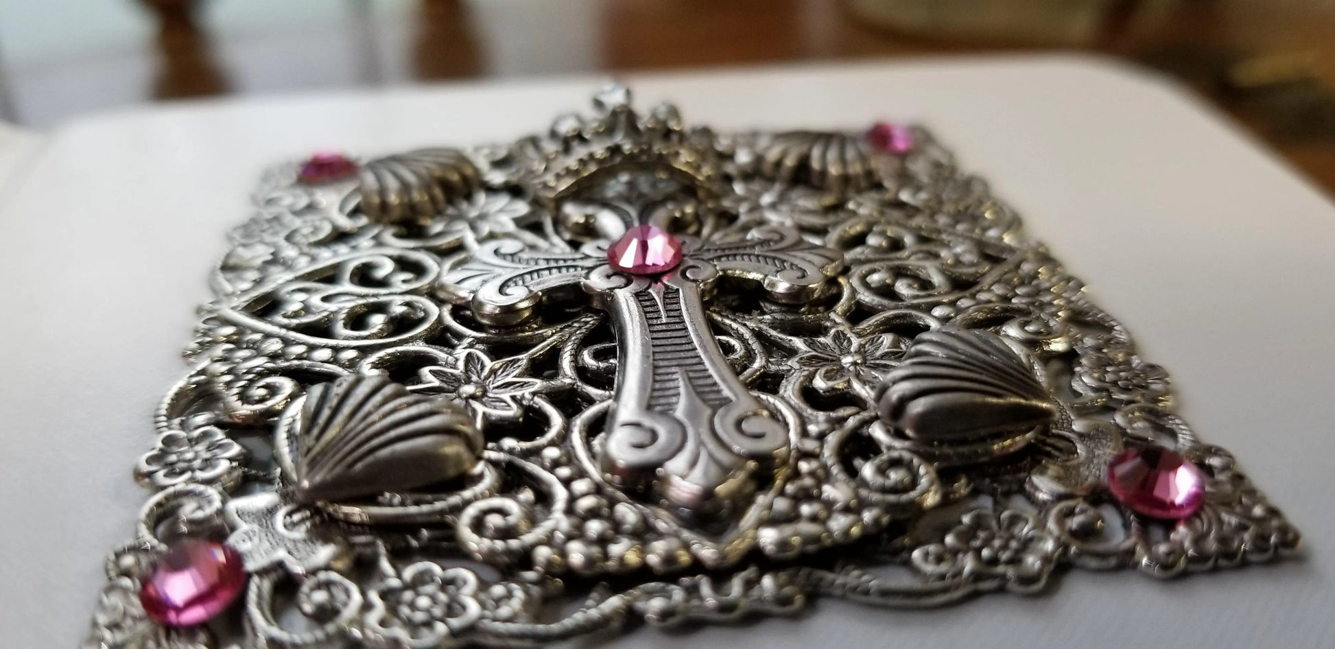 Close-up of ornate jeweled baby Bible cover with silver cross and pink gemstones