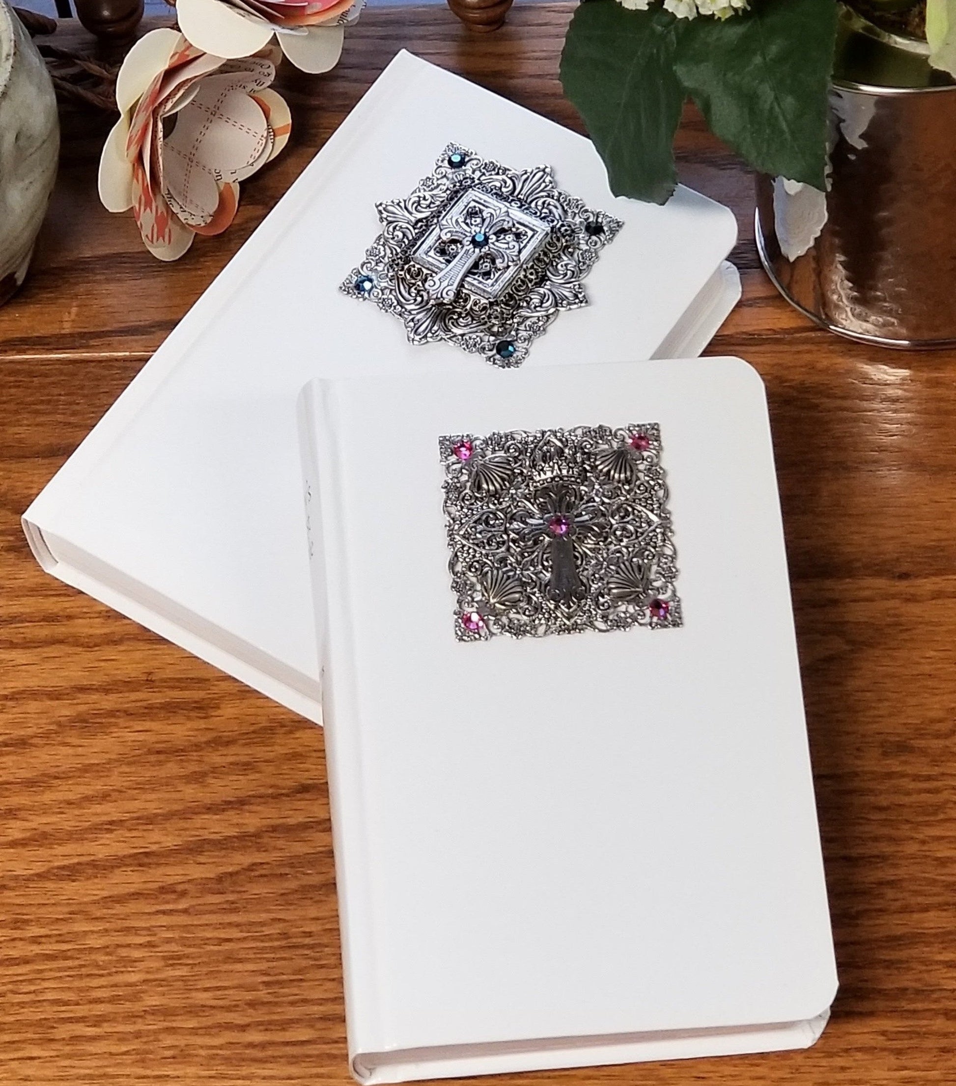 White jeweled baby Bibles with ornate silver covers, decorative crosses, and gemstone accents
