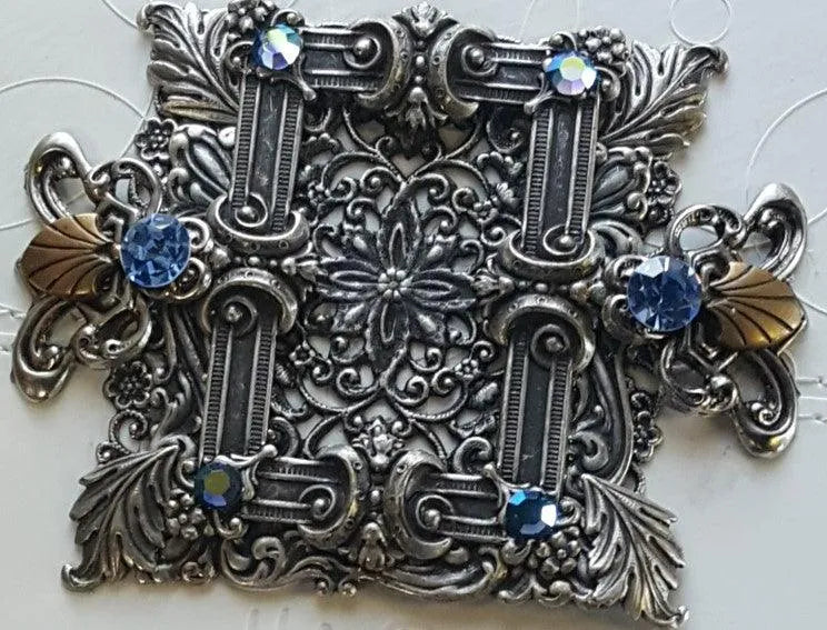 Ornate silver metal Bible cover with blue gemstones and intricate floral detailing