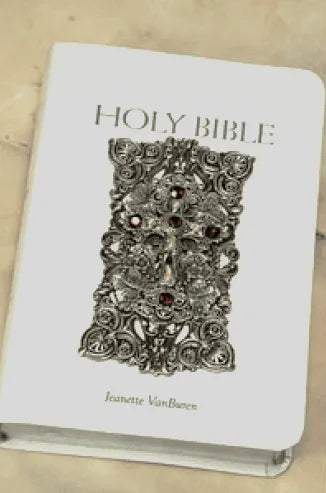 White jeweled Holy Bible with ornate silver metal cover and ruby accents on beige background